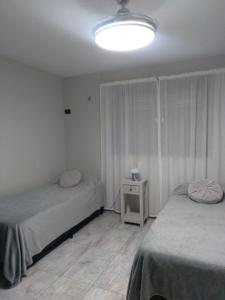 una camera con 2 letti singoli e luce di Arecas a Villa Carlos Paz