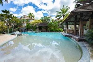 a swimming pool in a resort with palm trees at Lantana Lakes - Resort Style Living in Cairns North