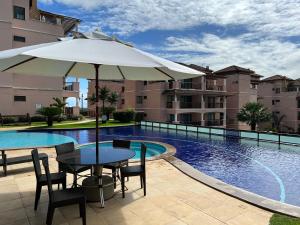 - une table avec un parasol à côté de la piscine dans l'établissement Beverly Hills terreo Raul Macedo Neg Imob, à Aquiraz