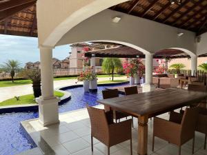 un patio avec une table et des chaises et une piscine dans l'établissement Beverly Hills terreo Raul Macedo Neg Imob, à Aquiraz
