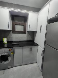 a kitchen with white cabinets and a washing machine at Porto Said apartment in Port Said