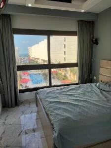 a bedroom with a bed and a large window at Porto Said apartment in Port Said