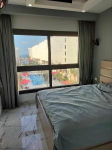 a bedroom with a bed and a large window at Porto Said chalet شاليه بورتو سعيد ثلاث غرف in Port Said