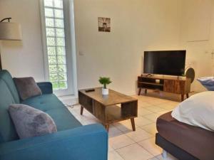 un soggiorno con divano blu e TV di CHATENAY 4 · Cozy Studio with car park and terrace a Châtenay-Malabry