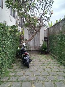 a motorcycle parked on a stone path next to a fence at Ngetis Home Stay in Sanur