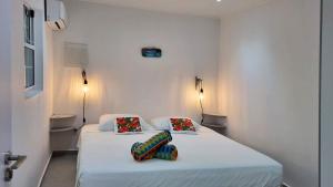 a white room with a bed with two pillows at Hibiscus Beach House in Willemstad