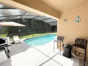 a swimming pool with chairs and an umbrella at Fully Renovated, Quiet, Spacious Disney Themed Pool Home with Office in Kissimmee