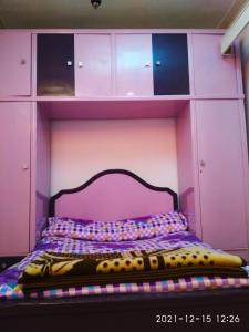 a bed in a pink room with a purple headboard at Nice house in Alexandria