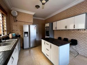 a kitchen with white cabinets and a refrigerator at T’s place in Apenkwa