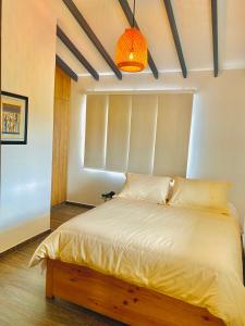 a bedroom with a white bed with a light fixture at Ruitoque Apartamento Campestre Maravillosa Vista in Floridablanca