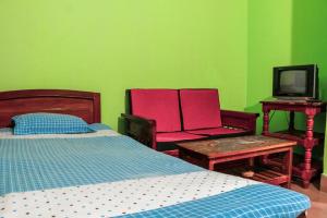 a bedroom with a bed and two chairs and a tv at Hotel Indropuri International in Dhaka