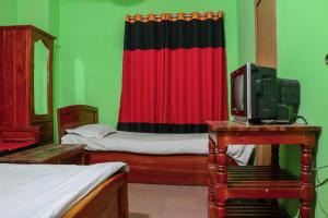 een kamer met twee bedden en een tv op een tafel bij Hotel Indropuri International in Dhaka