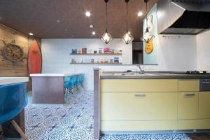 a kitchen with a sink and a counter with blue chairs at The BEEHIVE OTARU in Otaru