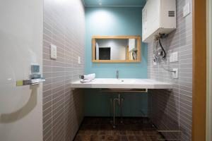 a bathroom with a sink and a mirror at The BEEHIVE OTARU in Otaru