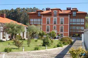 un gran edificio de naranjos con árboles delante de él en Hotel La Casona de Lupa, en El Peñedo