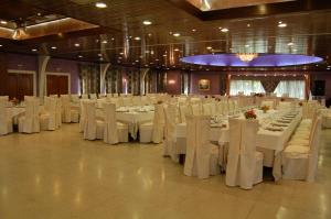 un salón de banquetes con mesas blancas y sillas blancas en Hotel La Casona de Lupa, en El Peñedo