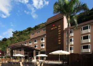 ein Hotel mit Tischen und Sonnenschirmen davor in der Unterkunft Hoya Hot Springs Resort & Spa in Wenquan