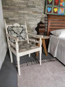 a white rocking chair sitting next to a bed at Buddha Suítes in Pipa