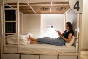 a woman sitting on a bunk bed reading a book at Citylights By MUSAFIR in Udaipur