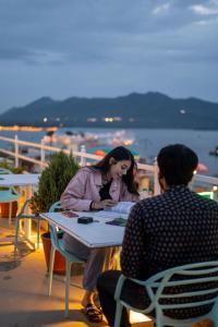 烏代浦的住宿－Citylights By MUSAFIR，坐在桌子上与男人说话的女人