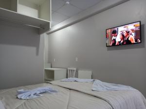 a bedroom with a bed with a flat screen tv on the wall at Sognare Hotel in Caçador