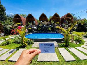 a person holding up a sign in front of a resort at Manik Tirta Cabin's in Kintamani