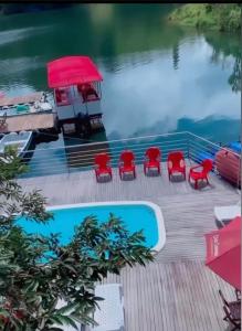 une terrasse avec des chaises rouges et une piscine dans l'établissement Finca Santa Monica Guatape Privada Lujosa Piscina Jacuzzi Sauna muelle Represa jetski planchon, à Guatapé