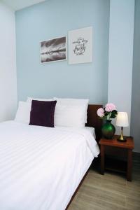 a bedroom with a white bed and a vase with flowers at Sunny House in Da Nang