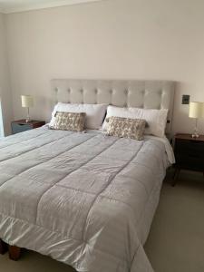 1 cama blanca grande con 2 almohadas en Departamento frente al mar en Arica en Arica