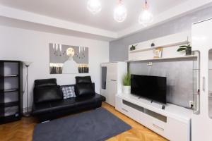 sala de estar con silla de cuero negro y TV de pantalla plana en Central Apartment Targu Mures, en Târgu Mureș