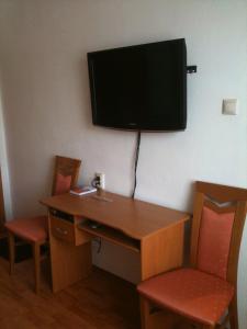 皮耶什佳尼的住宿－巴黎別墅旅館，一张桌子、两把椅子和墙上的电视