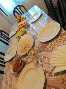 a table topped with white plates and bowls of food at Nuwara eliya mountain view homestay in Nuwara Eliya