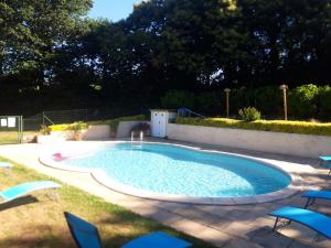 una piscina con sillas azules y un patio en Gîte La Grange en Langoëlan