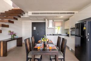 eine Küche mit einem Esstisch mit Stühlen und einem schwarzen Kühlschrank in der Unterkunft Raya Beachloft in Rawai Beach