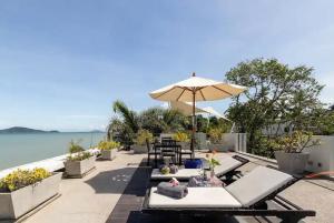 a patio with chairs and an umbrella and the water at Raya Beachloft in Rawai Beach