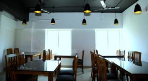 a dining room with tables and chairs and lights at PEROOR INN in Trivandrum