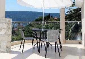 a table and chairs on a balcony with an umbrella at Swiss Residence Montenegro in Herceg-Novi