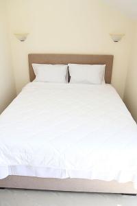 a large bed with white sheets and pillows at Swiss Residence Montenegro in Herceg-Novi