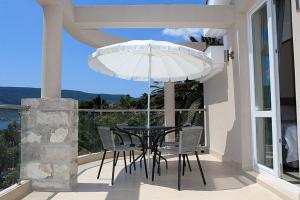 a table and chairs on a balcony with an umbrella at Swiss Residence Montenegro in Herceg-Novi