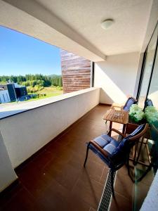 a balcony with a table and chairs and a large window at Dream Studio Silver Mountain in Poiana Brasov