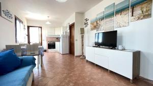 Sardegna - Villa Mirto & Flowers في أولبيا: غرفة معيشة مع أريكة وتلفزيون على خزانة