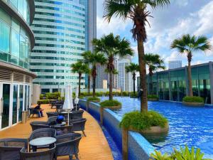 uma piscina num edifício com palmeiras e cadeiras em Vortex Suites KLCC By Welt em Kuala Lumpur