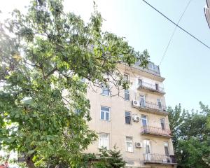 a tall building with balconies and a tree at Sweet Dreams Suites Cismigiu Gardens in Bucharest