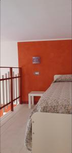 1 dormitorio con paredes de color naranja, 1 cama y 1 mesa en B&B Les Saisons de Jade, en Nocera Superiore