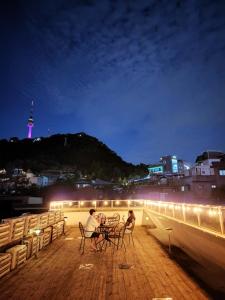 two people sitting at tables on a deck at night at Namsan Guesthouse in Seoul +53 photos