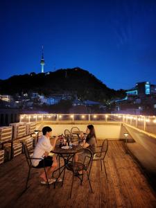 two people sitting at a table on a balcony at night at Namsan Guesthouse in Seoul +53 photos