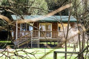 een blokhut met een veranda en een groen dak bij Drumreagh Cabins in Deloraine