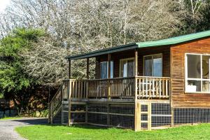 a wooden cabin with a large deck on the grass at Drumreagh Cabins in Deloraine