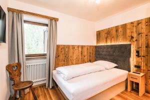 1 dormitorio con cama blanca y ventana en Chalet Scherlin en Ortisei