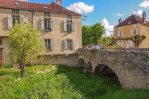 un viejo puente de piedra frente a algunos edificios en confortable maison familiale à l'entrée du village médiéval, en Noyers-sur-Serein